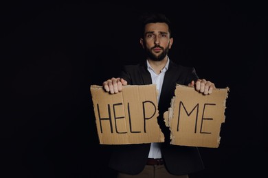 Unhappy man with HELP ME sign on dark background