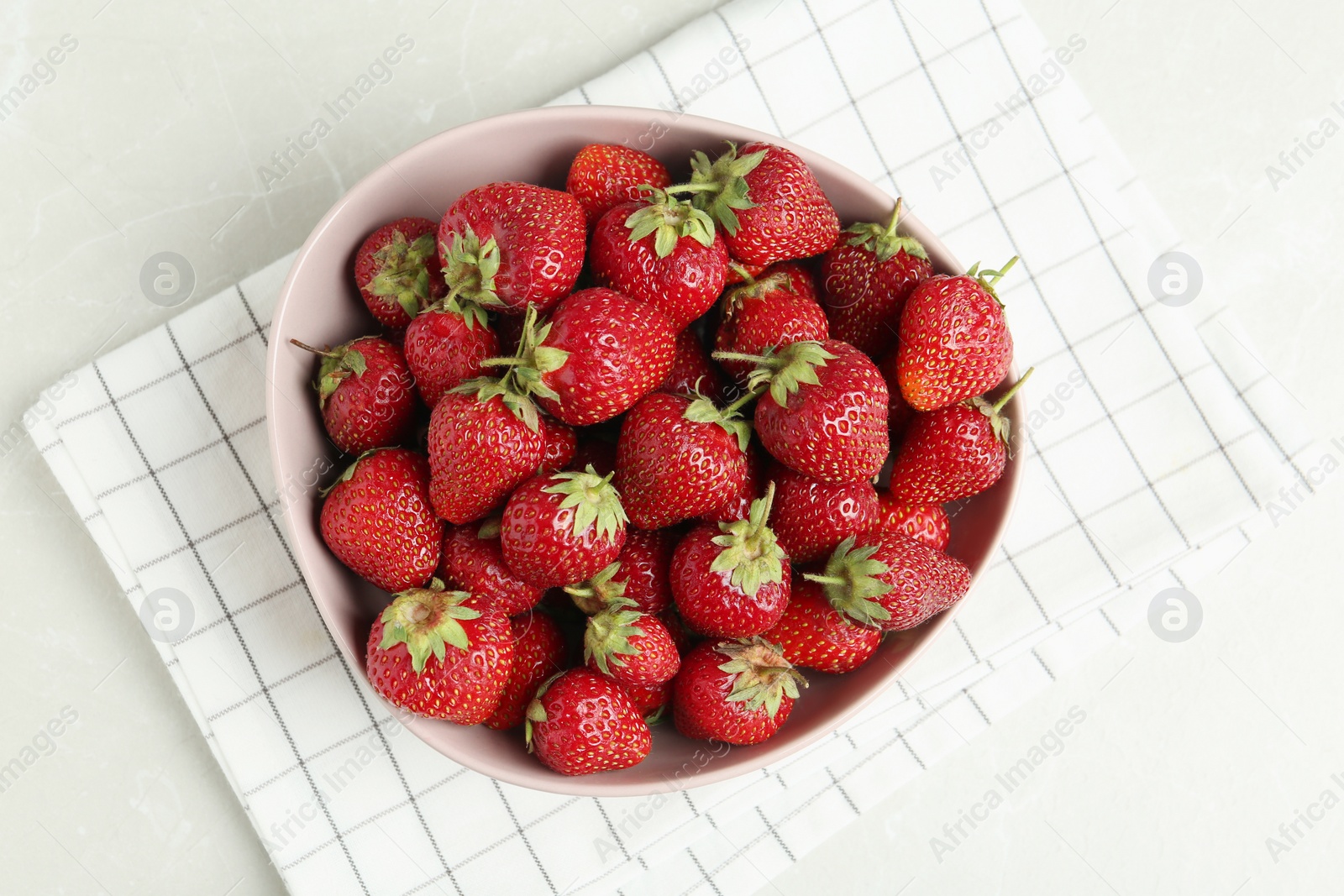 Photo of Delicious ripe strawberries in bowl on light grey marble table, flat lay