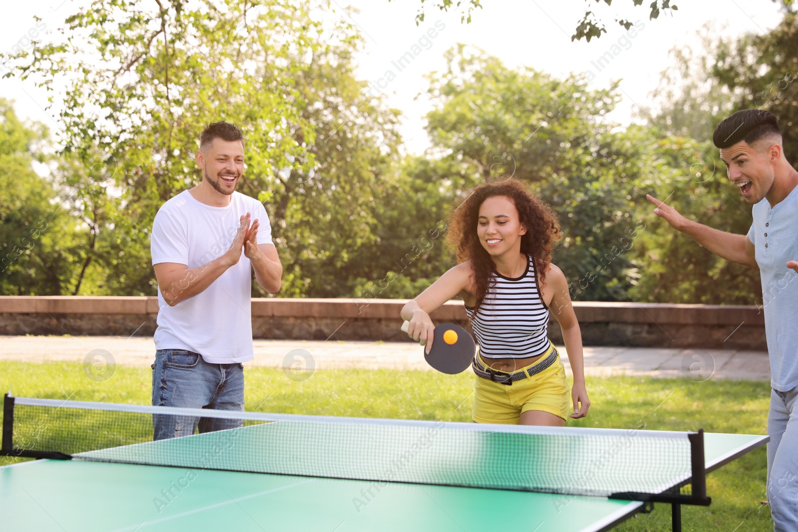 Photo of Friends playing ping pong outdoors on summer day