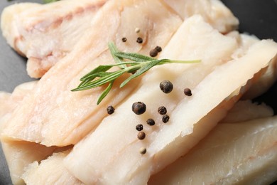 Photo of Pieces of raw cod fish, rosemary and peppercorns on table, closeup