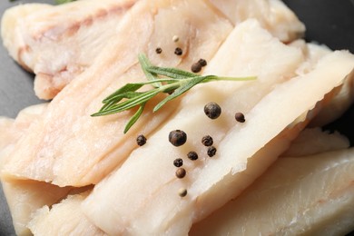 Pieces of raw cod fish, rosemary and peppercorns on table, closeup