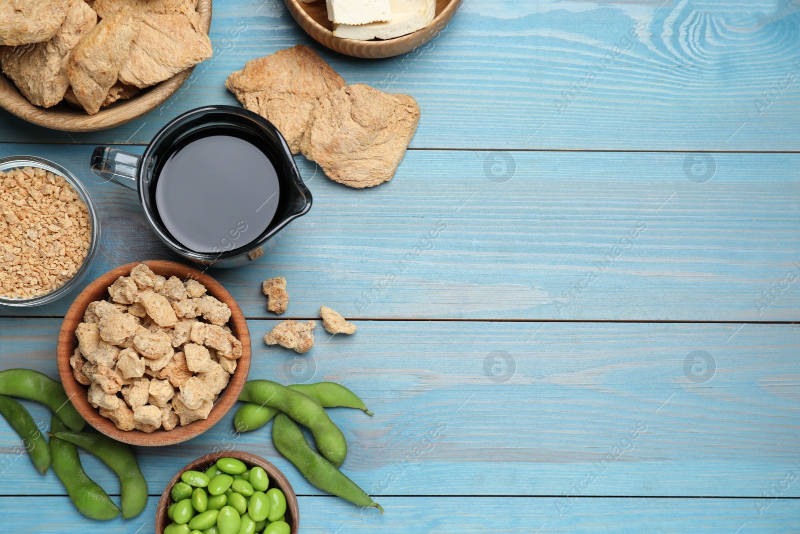 Photo of Different organic soy products on turquoise wooden table, flat lay. Space for text