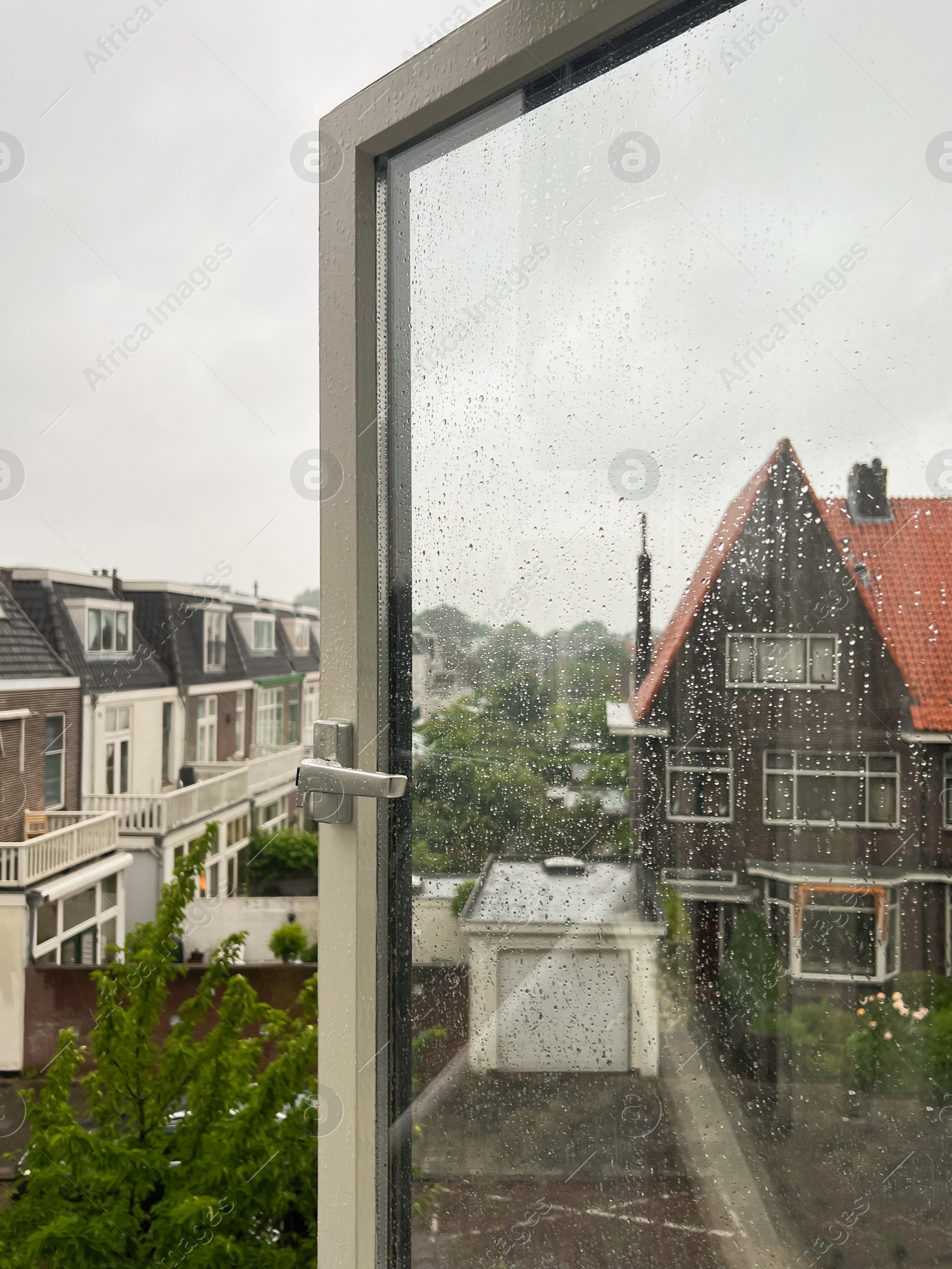 Photo of Beautiful cityscape with buildings on rainy day, view through open window