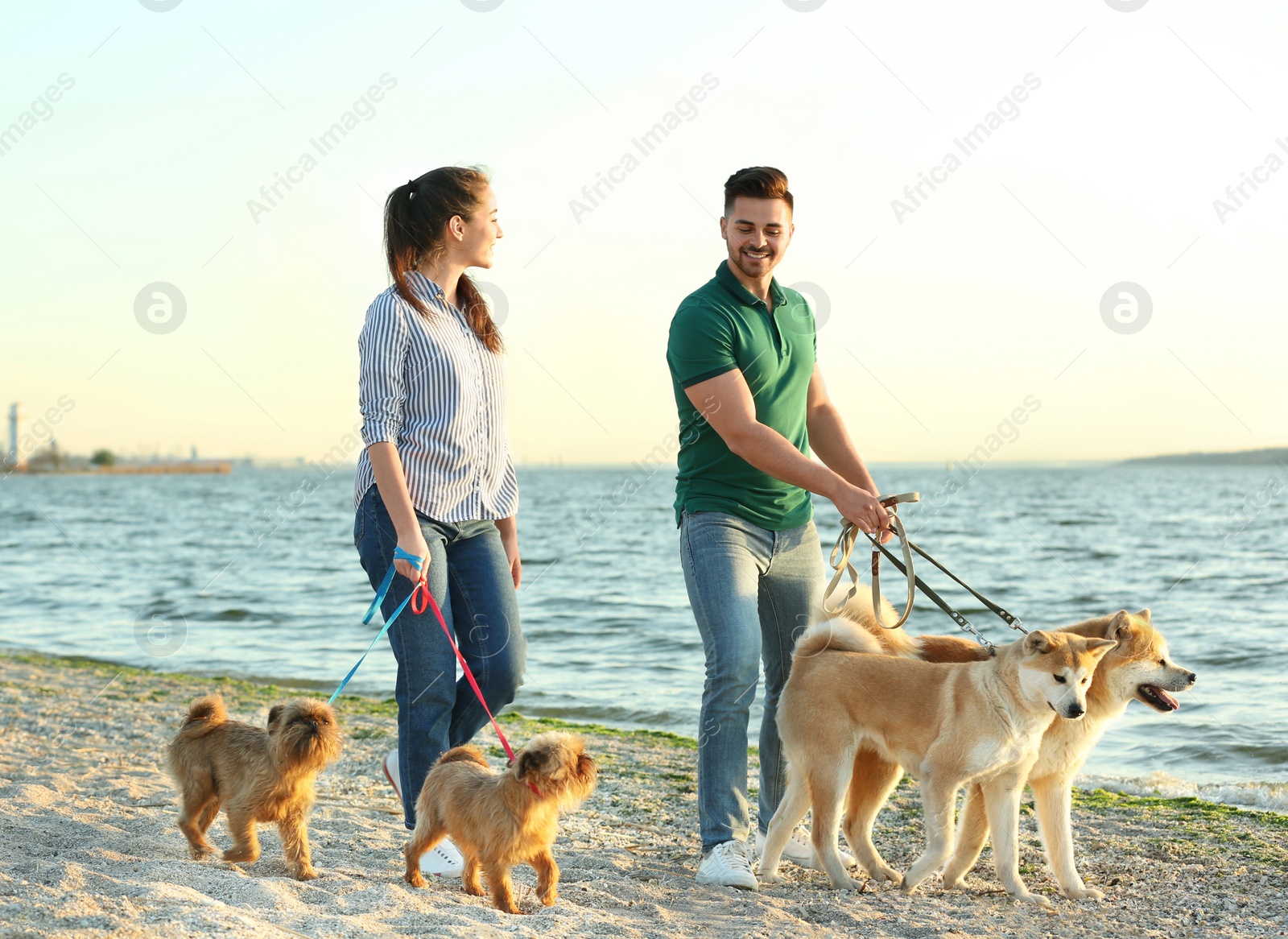 Photo of Young couple walking their adorable dogs near river