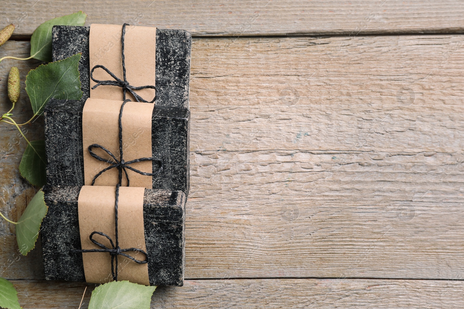 Photo of Natural tar soap on wooden table, flat lay. Space for text