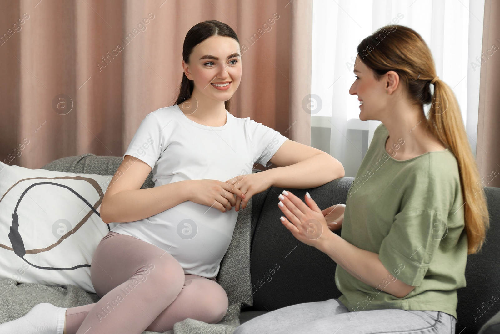 Photo of Doula working with pregnant woman on sofa at home. Preparation for child birth