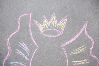 Child's chalk drawing of crown and wings on asphalt, top view