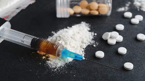 Syringe, pills and powder on black background, closeup. Hard drugs