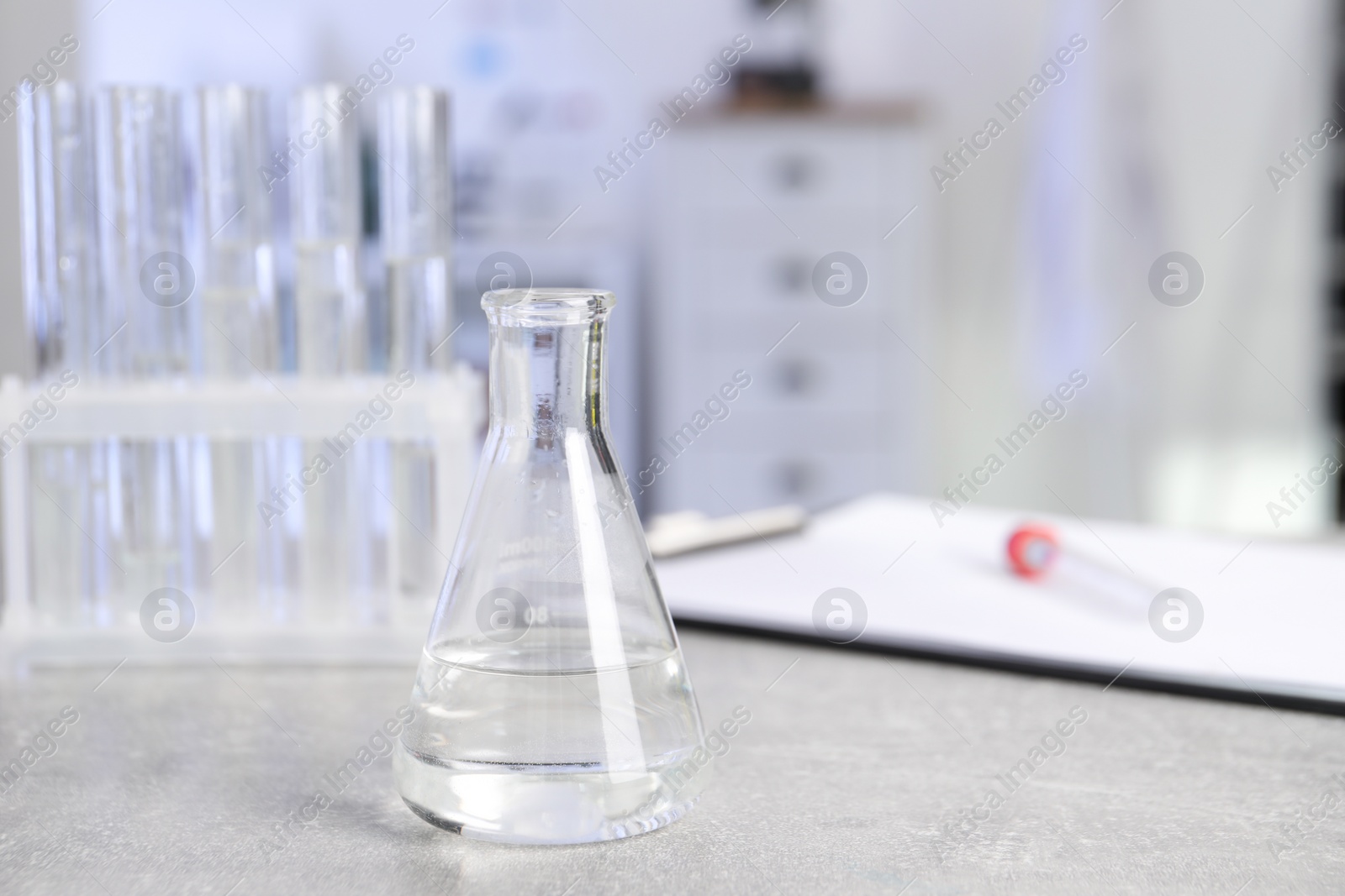 Photo of Laboratory analysis. Flask and test tubes on light grey table indoors, space for text