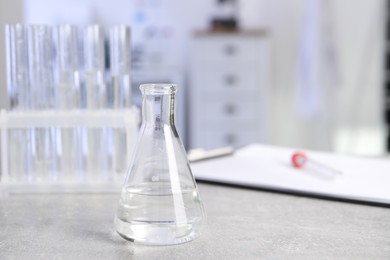 Photo of Laboratory analysis. Flask and test tubes on light grey table indoors, space for text