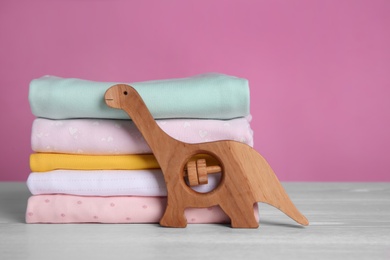 Stack of children's clothes and toy on white wooden table