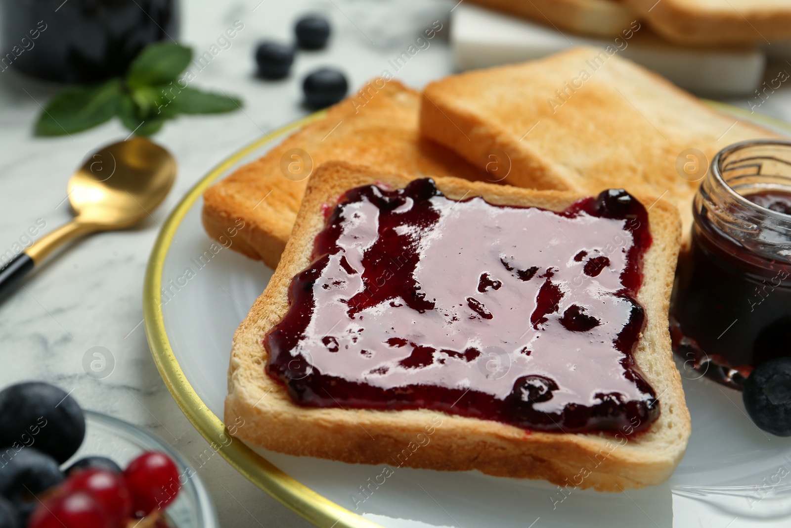 Photo of Delicious toasts with jam served on white marble table, closeup