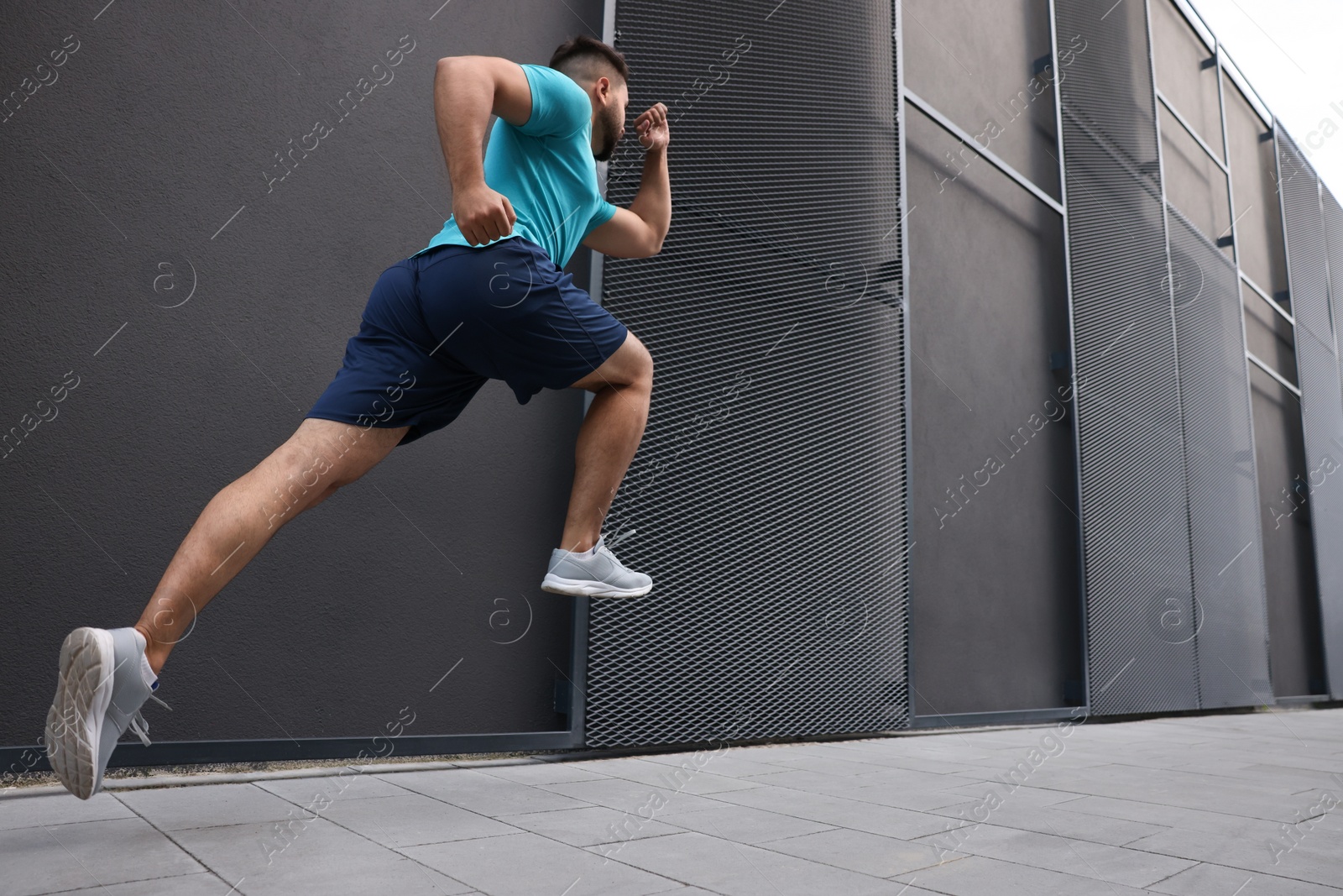 Photo of Man running near building outdoors, low angle view. Space for text