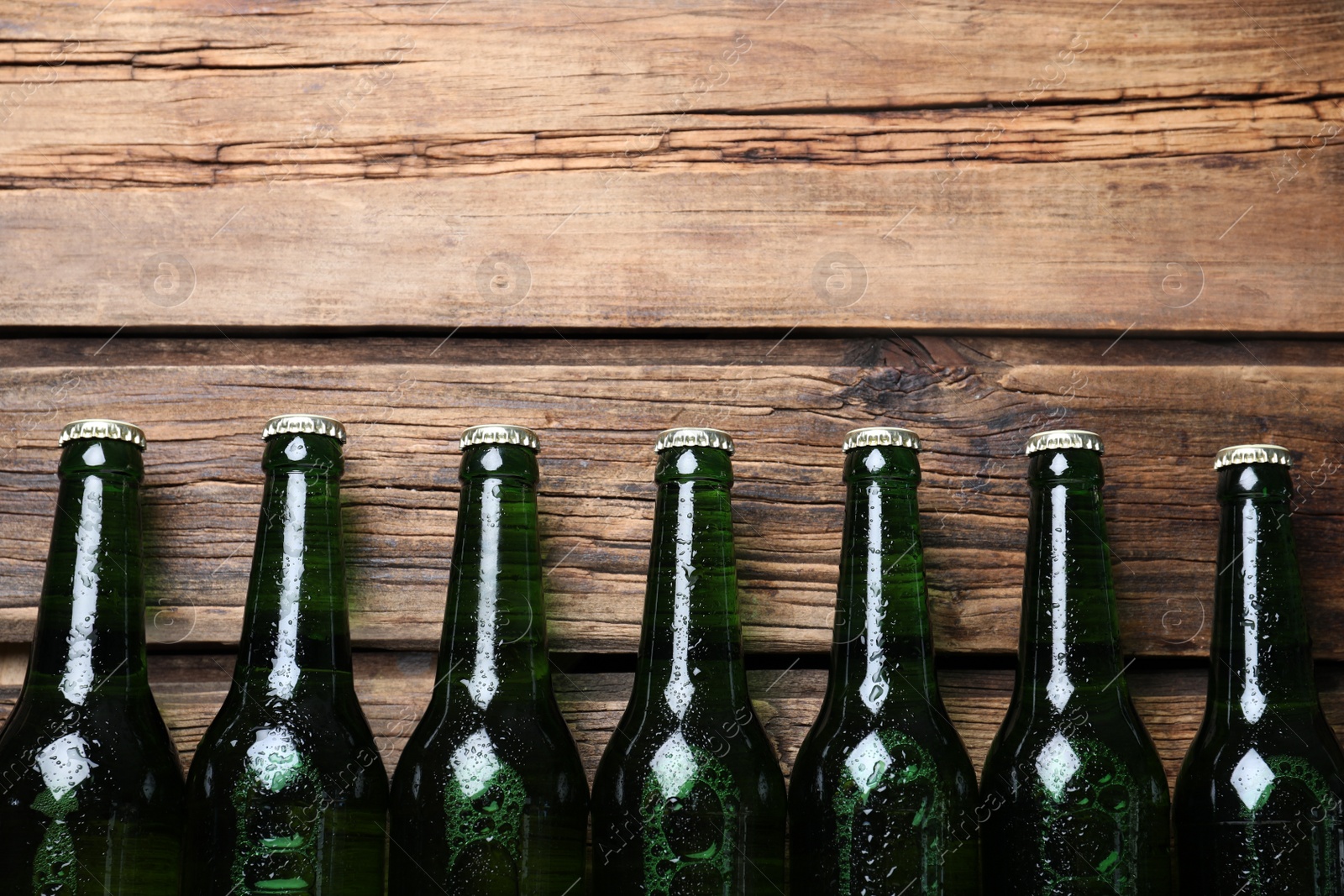 Photo of Bottles of beer on wooden table, flat lay. Space for text