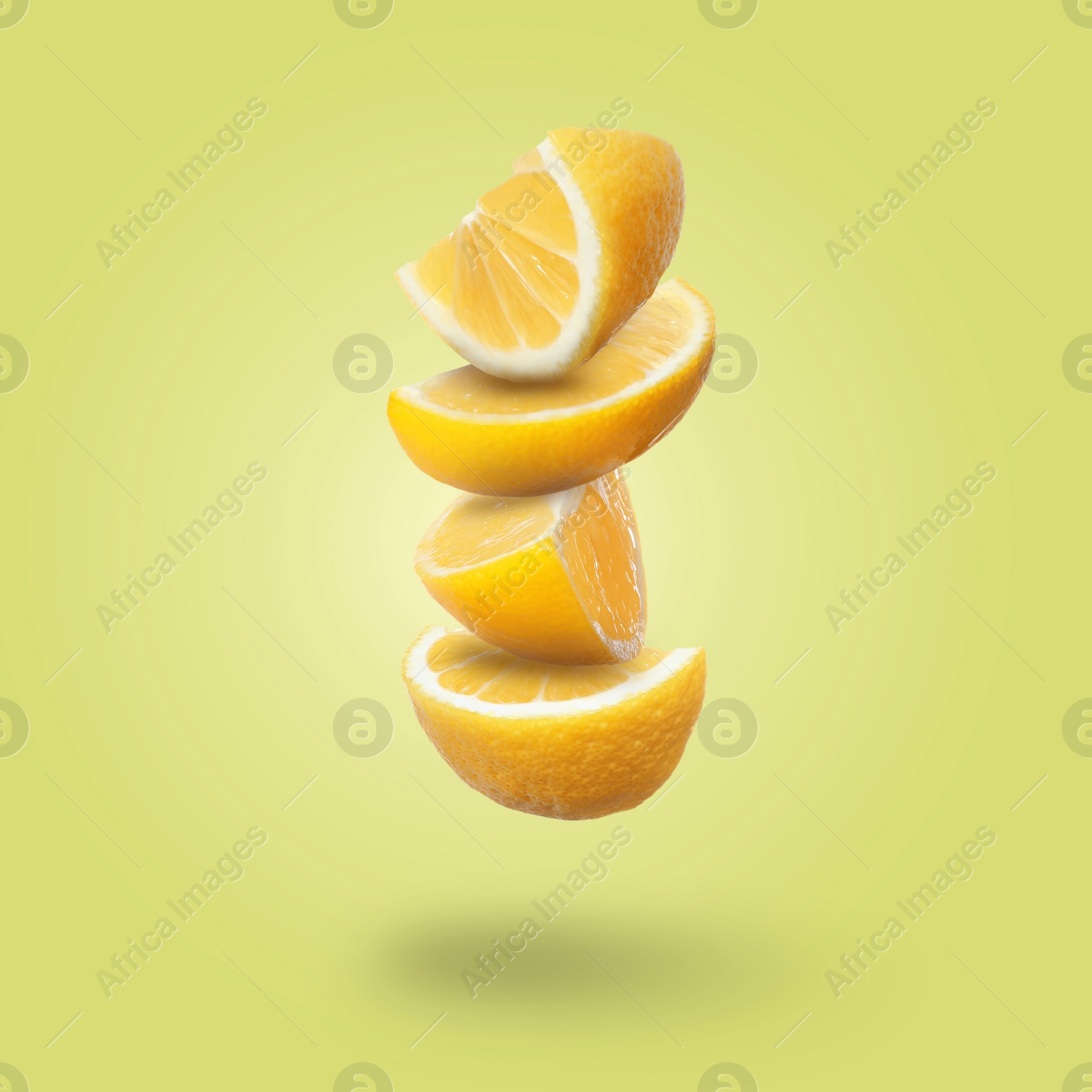 Image of Cut fresh ripe lemons falling on yellow background