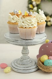 Photo of Tasty Easter cupcakes with vanilla cream and festive decor on light wooden table