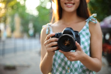Photo of Young photographer with professional camera outdoors, closeup
