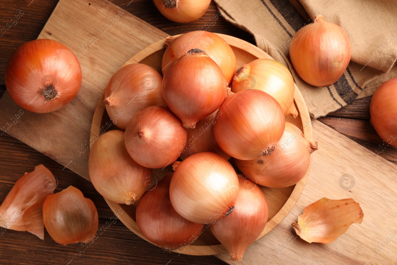 Photo of Many ripe onions on wooden table, flat lay