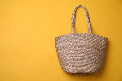 Stylish straw bag on yellow background, top view with space for text. Summer accessory