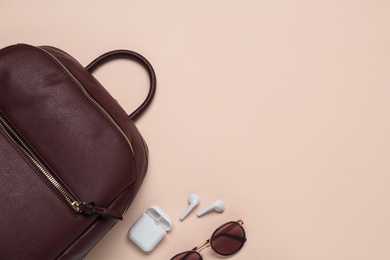 Photo of Backpack with sunglasses and earphones on pink background, flat lay. Space for text