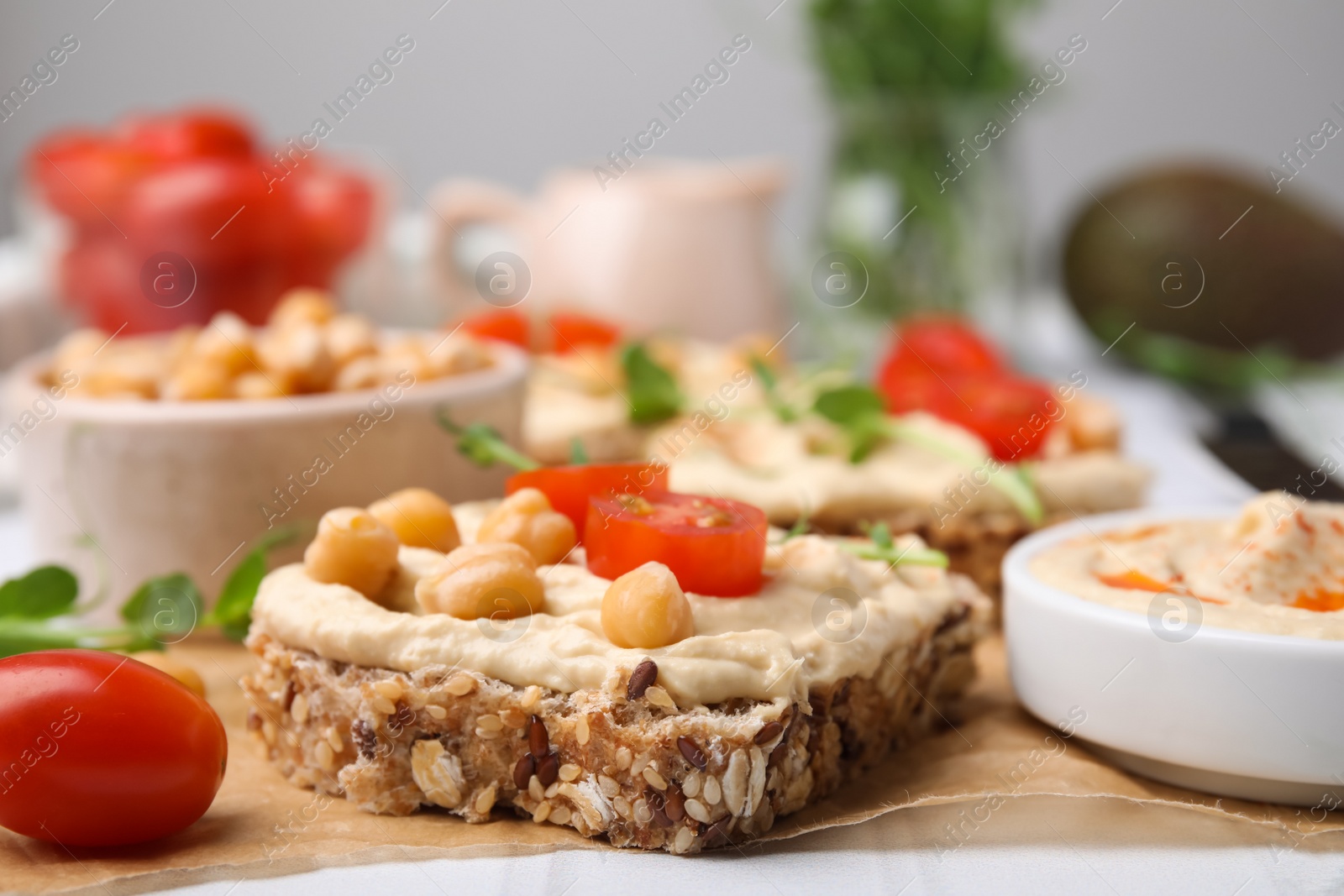 Photo of Delicious sandwiches with hummus and ingredients on wooden board, closeup