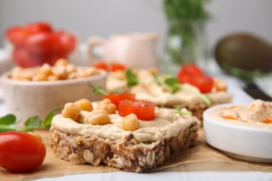 Photo of Delicious sandwiches with hummus and ingredients on wooden board, closeup