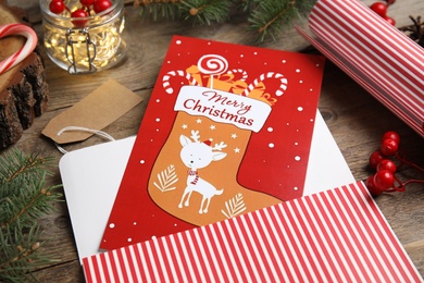 Photo of Christmas card and festive decor on wooden background, closeup