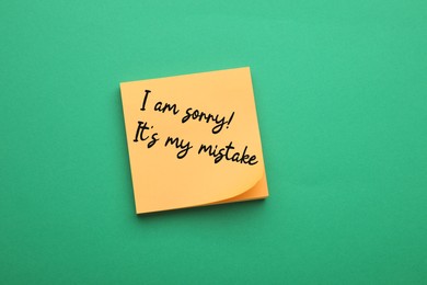 Image of Orange sticky note with phrase I Am Sorry, It's My Mistake on green background, top view