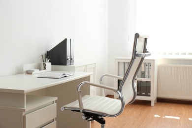 Photo of Stylish workplace interior with modern office chair and desk