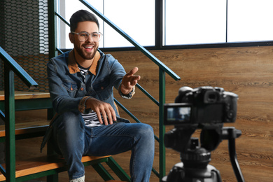 Photo of Young blogger recording video on camera indoors