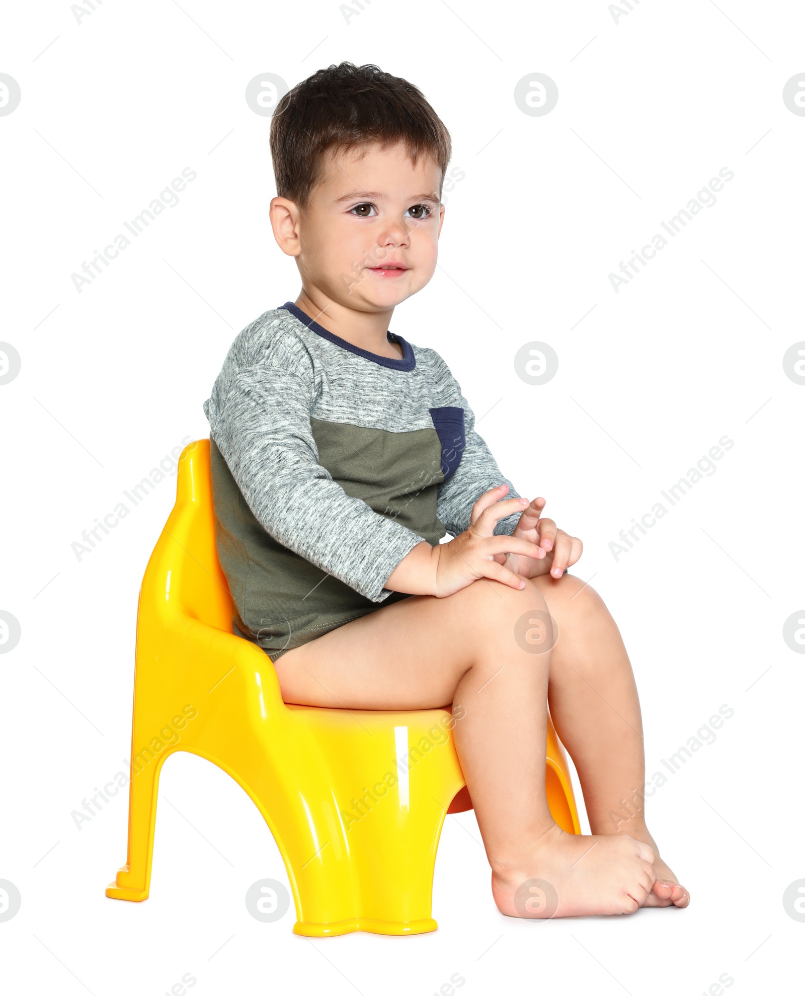 Photo of Portrait of little boy sitting on potty against white background