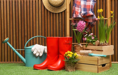 Composition with different gardening tools on artificial grass at wooden wall