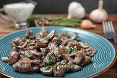 Photo of Plate of tasty fried mushrooms with sauce on table, closeup