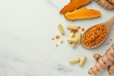 Aromatic turmeric powder, pills and raw roots on white marble table, flat lay. Space for text