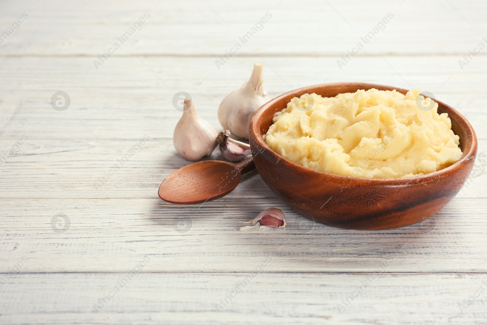 Photo of Bowl with mashed potatoes on wooden table. Space for text