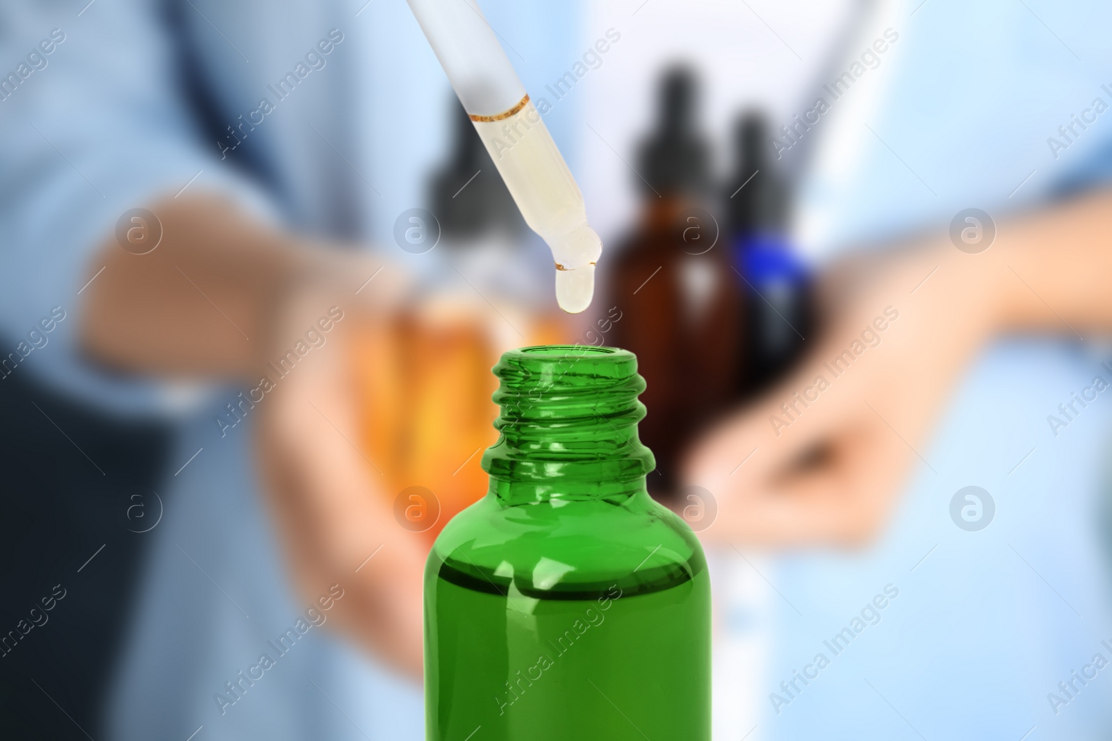 Image of Little bottle with essential oil and dropper against blurred background