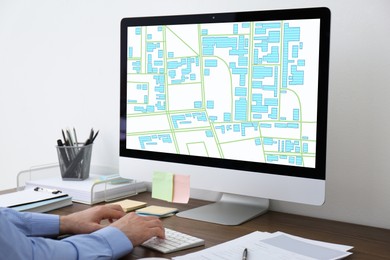 Image of Man analyzing cadastral map on computer at table, closeup 