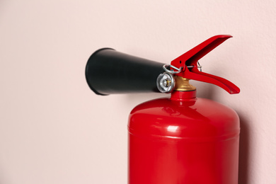 Photo of Fire extinguisher on pink background, closeup view