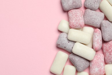 Photo of Different tasty colorful bubble gums on pink background, flat lay. Space for text