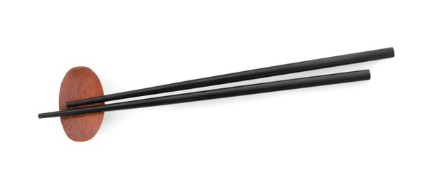 Photo of Pair of black chopsticks with rest isolated on white, top view