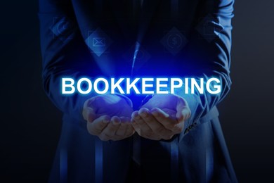 Bookkeeping concept. Businessman holding word on dark blue background, closeup