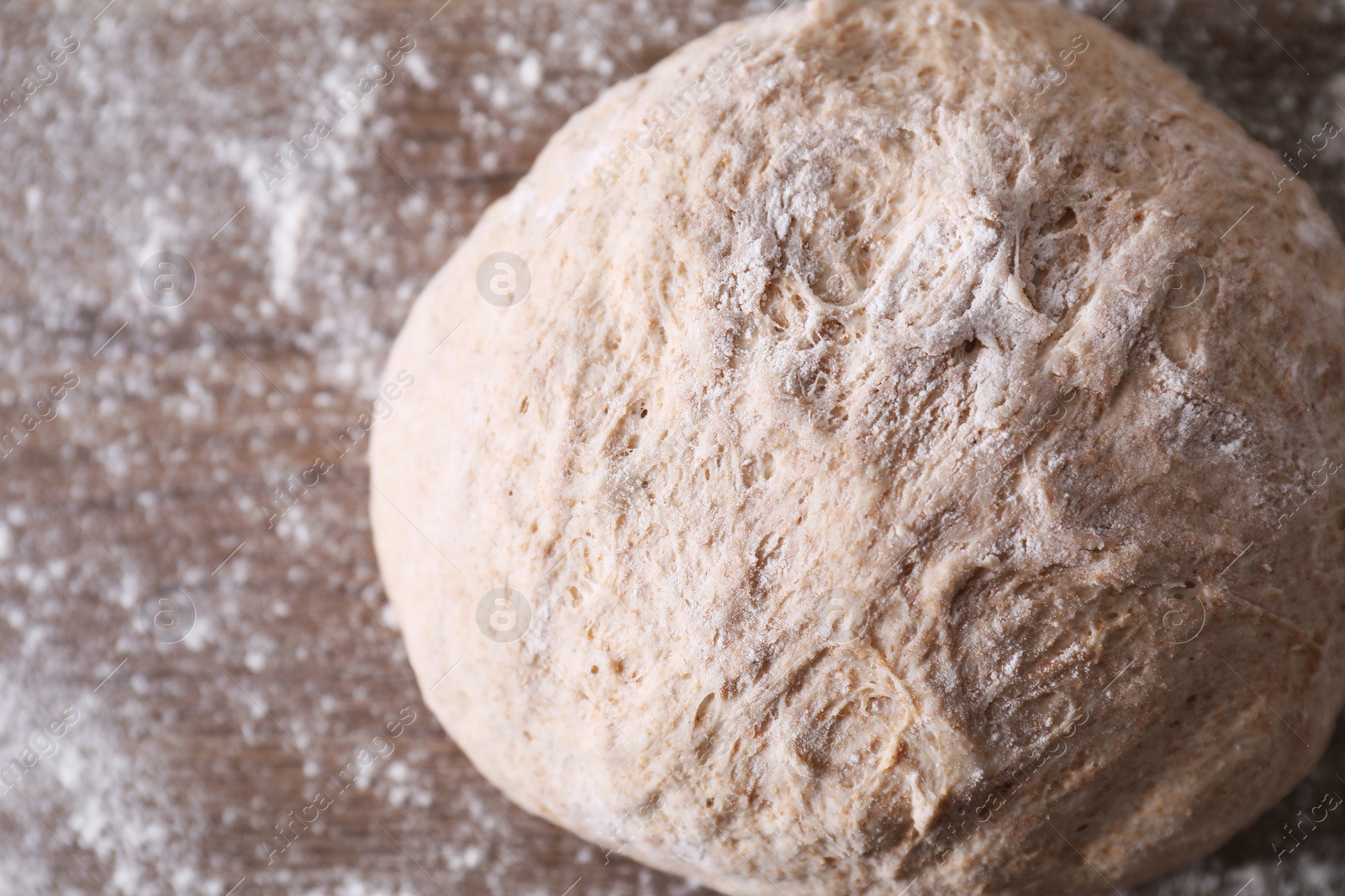 Photo of Fresh sourdough and flour on wooden table, closeup. Space for text