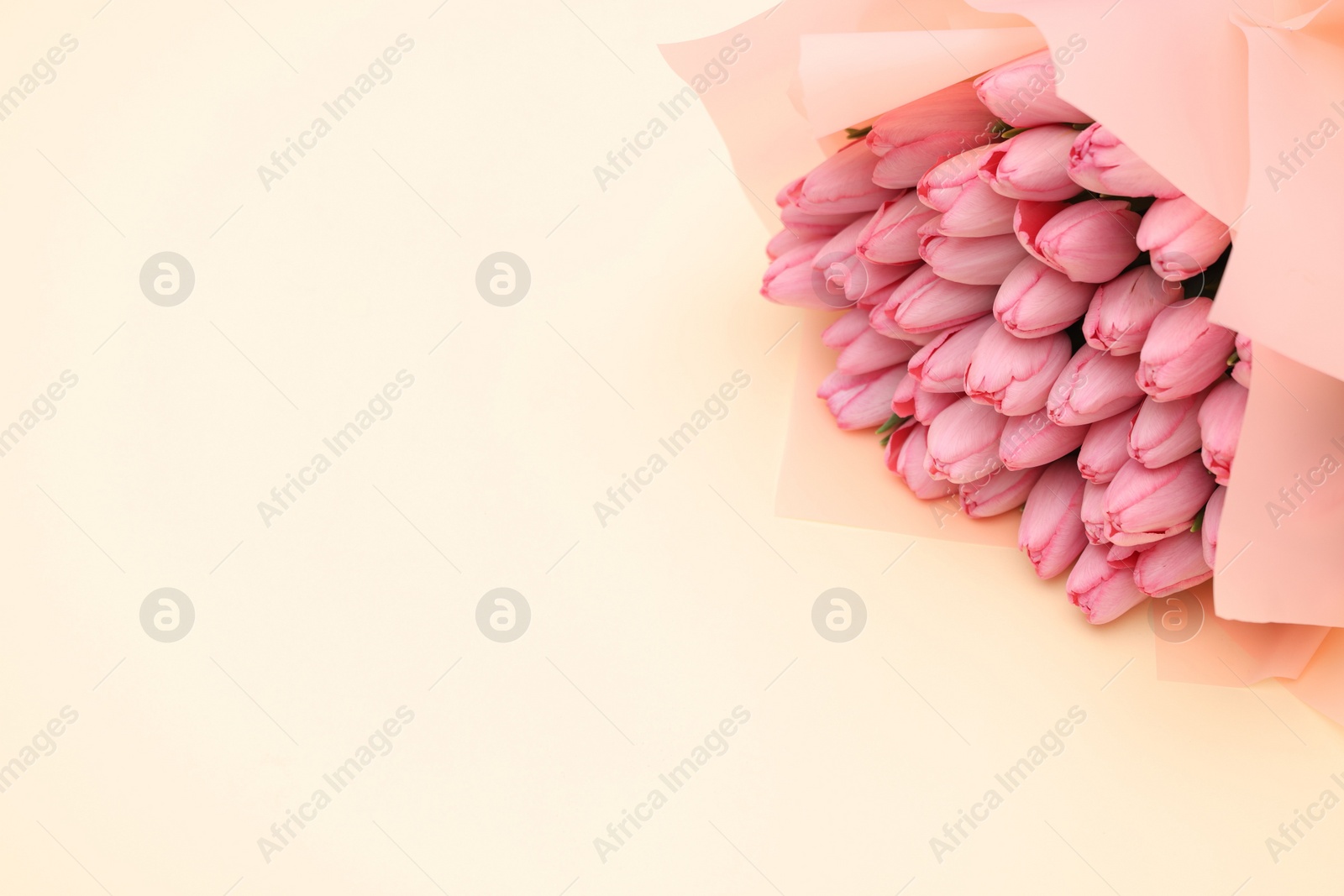 Photo of Bouquet of beautiful pink tulips on beige background, above view. Space for text