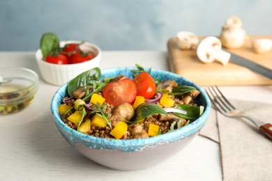 Delicious buckwheat porridge with vegetables and mushrooms on wooden table