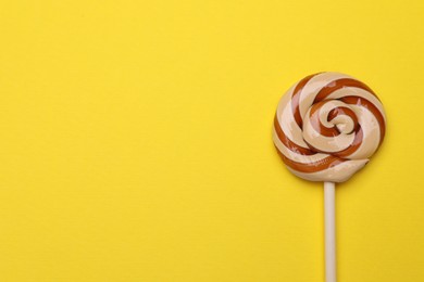 Photo of Delicious lollipop on yellow background, top view. Space for text