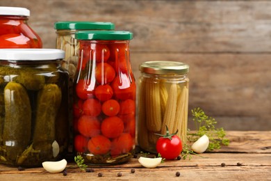 Jars of pickled vegetables on wooden table