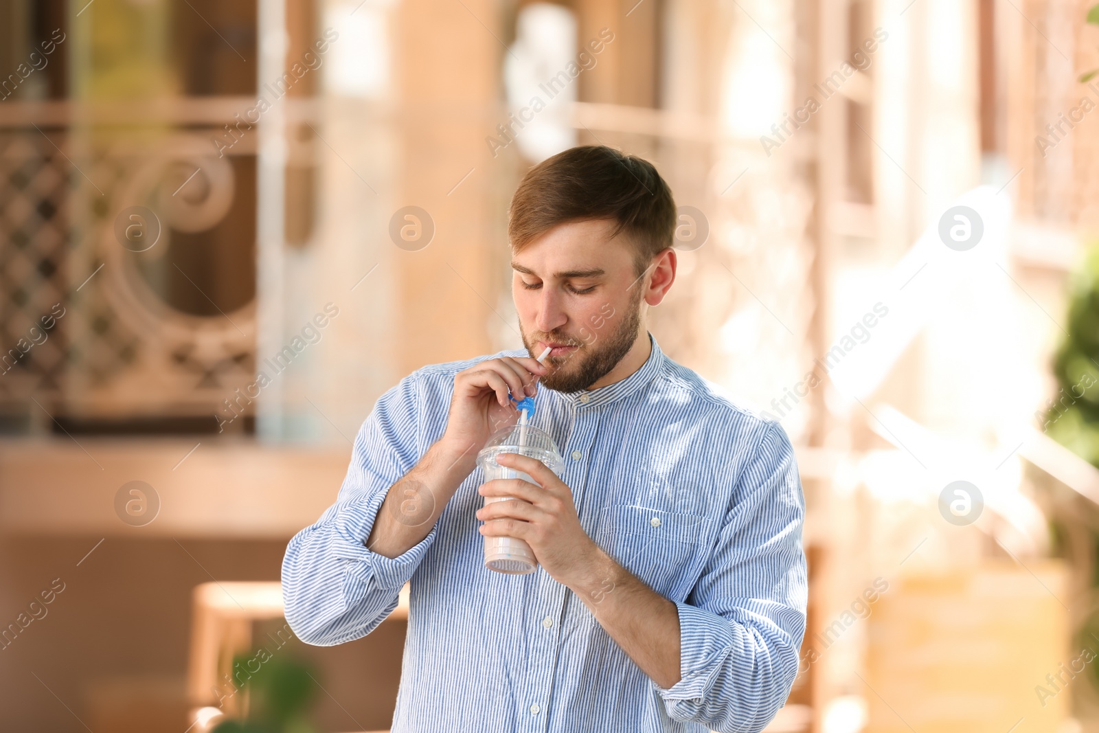 Photo of Young man with cup of delicious milk shake outdoors
