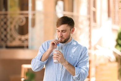 Photo of Young man with cup of delicious milk shake outdoors