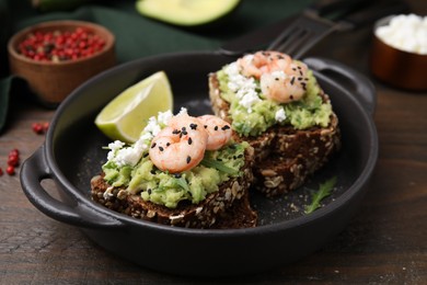 Photo of Delicious sandwiches with guacamole, shrimps and black sesame seeds on wooden table