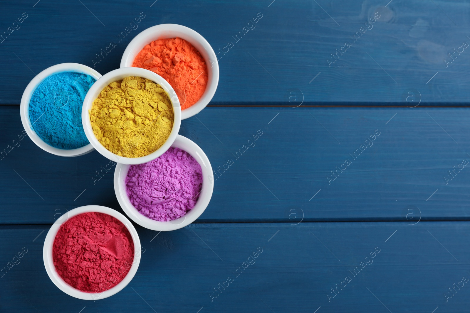 Photo of Colorful powder dyes on blue wooden background, flat lay with space for text. Holi festival